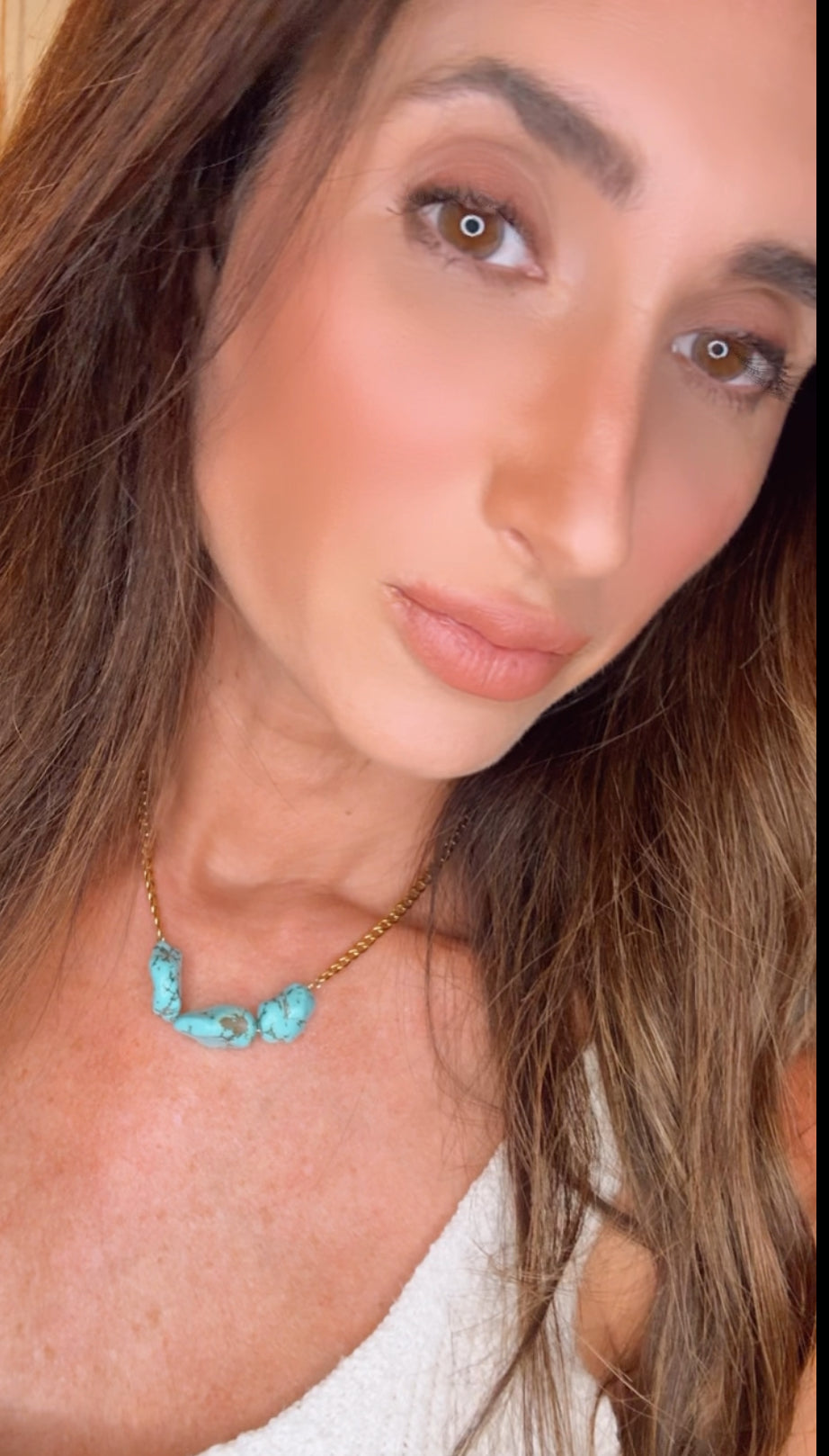 Close-up of a person wearing a turquoise necklace with a blurred background